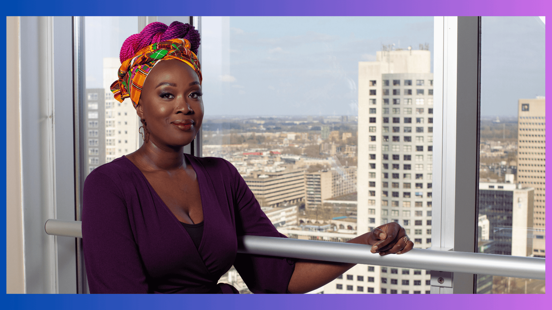 Vivian Acquah Inclusie Strategist Amplify DEI Vivian Acquah, a woman in a purple dress and an African head wrap with ombre purple blue braids leaning on a railing